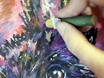 A hand working a stick of oil pastel into the ear of a portrait